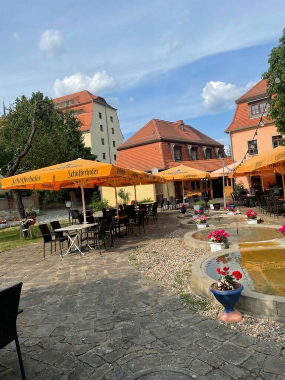 Innenhof mit Kopfsteinpflaster, Tischen mit gelben Sonnenschirmen und historischen Gebäuden im Hintergrund