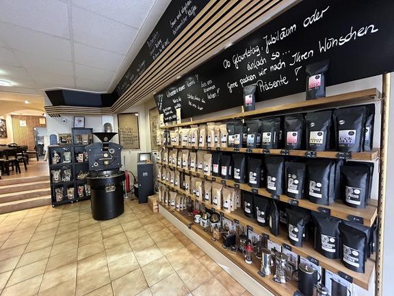 Die Innenansicht eines Cafés oder einer Rösterei. Im Regal liegen diverse Kaffeeprodukte. 