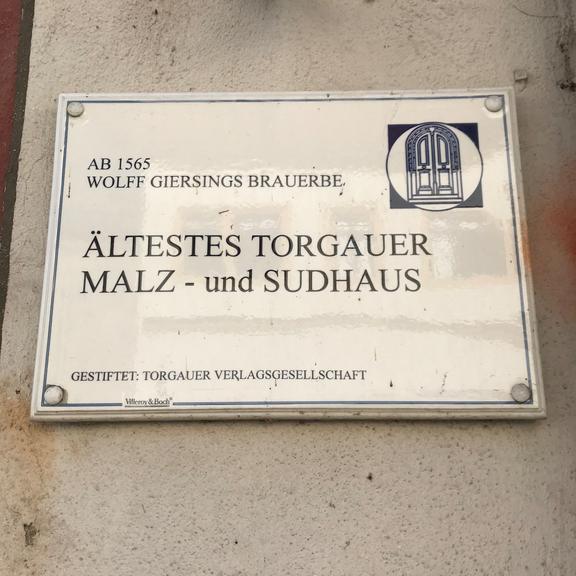 Schild mit der Aufschrift 'Ab 1565 Wolff Giersings Brauerbe Ältestes Torgauer Malz- und Sudhaus' an einer Wand