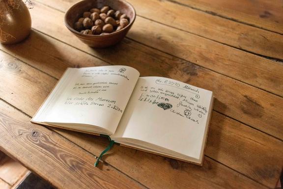 Offenes Notizbuch mit handschriftlichen Einträgen auf einem Holztisch