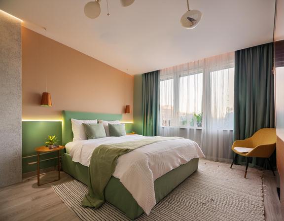Ein modernes Schlafzimmer mit grünen Akzenten und großen Fenstern.
