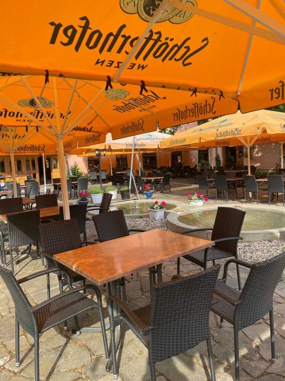 Außenbereich eines Cafés mit orangefarbenen Sonnenschirmen und mehreren Tischen und Stühlen