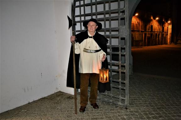 Im Torbogen des Torgauer Information Centers steht ein als Nachtwächter verkleideter Mann bei Nacht