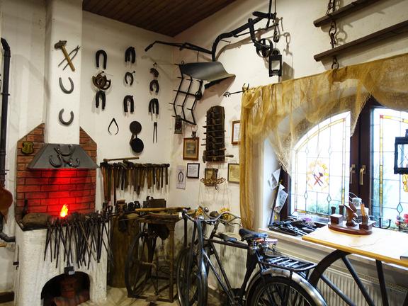 Innenansicht einer traditionellen Schmiede mit Werkzeugen und einem Schmiedefeuer.