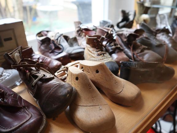 Verschiedene alte Schuhe und Holzschuhformen auf einem Holztisch im Schuhmuseum Torgau