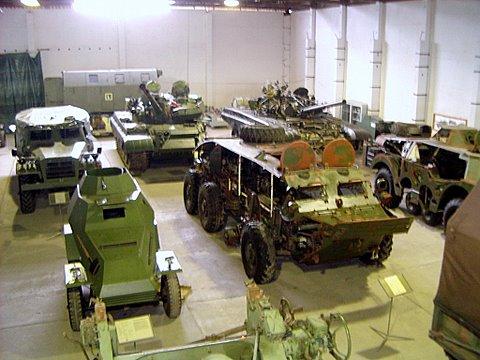 Ausstellung historischer Militärfahrzeuge in einer Halle mit mehreren gepanzerten Fahrzeugen und Militärtechnik