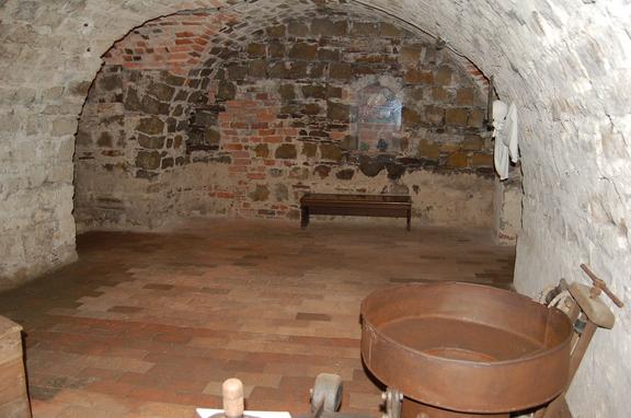 Historischer Braukeller mit gewölbter Decke aus Stein und Backstein, Holzboden und einem großen kupfernen Braukessel