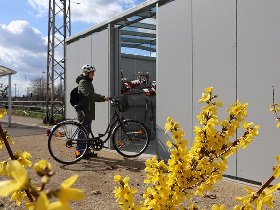 Stehende Person vor Fahrradbox am Bahnhof 