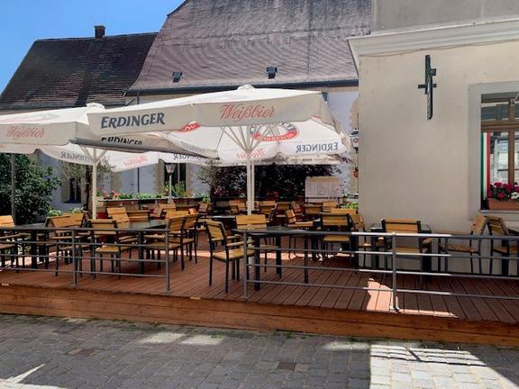 Im Außenbereich des Calabrese Torgau befindet sich eine Holzterrasse, mit Sitzmöglichkeiten und Sonnenschirmen bei sonnigem Wetter. 