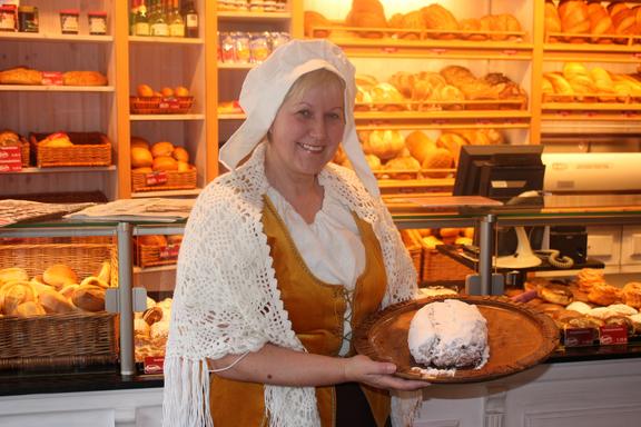 Stadtführerin Sophie als Bäckersfrau verkleidet, steht in einer beleuchteten Bäckerei.