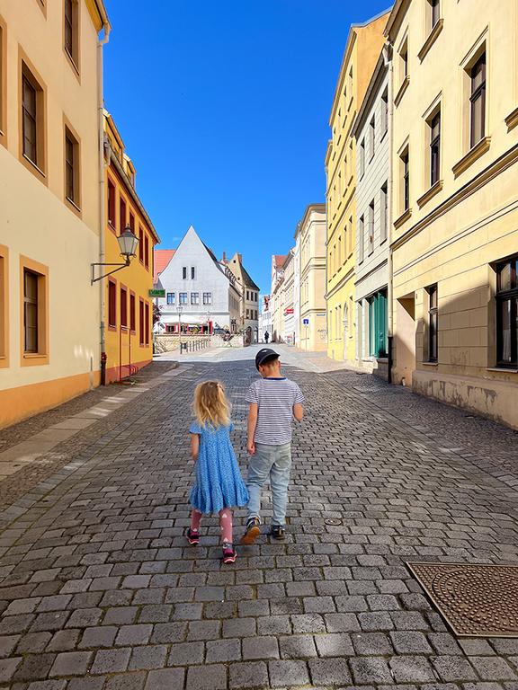 zwei auf der Schlossstraße stehende Kinder Junge und Mädchen bei sonnigem Wetter