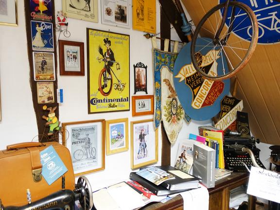 Eine Wand mit Vintage-Fahrradplakaten und Dekoration.