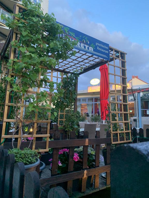 Außenansicht des Restaurants Kreta, eine verzweigte Holzkuppel, bei blauem dämmerndem Himmel.