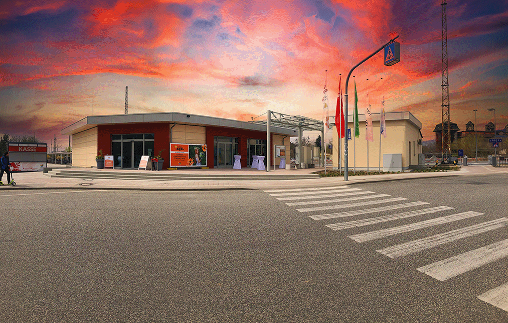 Service Center-Bahnhof Torgau davor eine Straße mit Zebrastreifen bei abendrotem Himmel