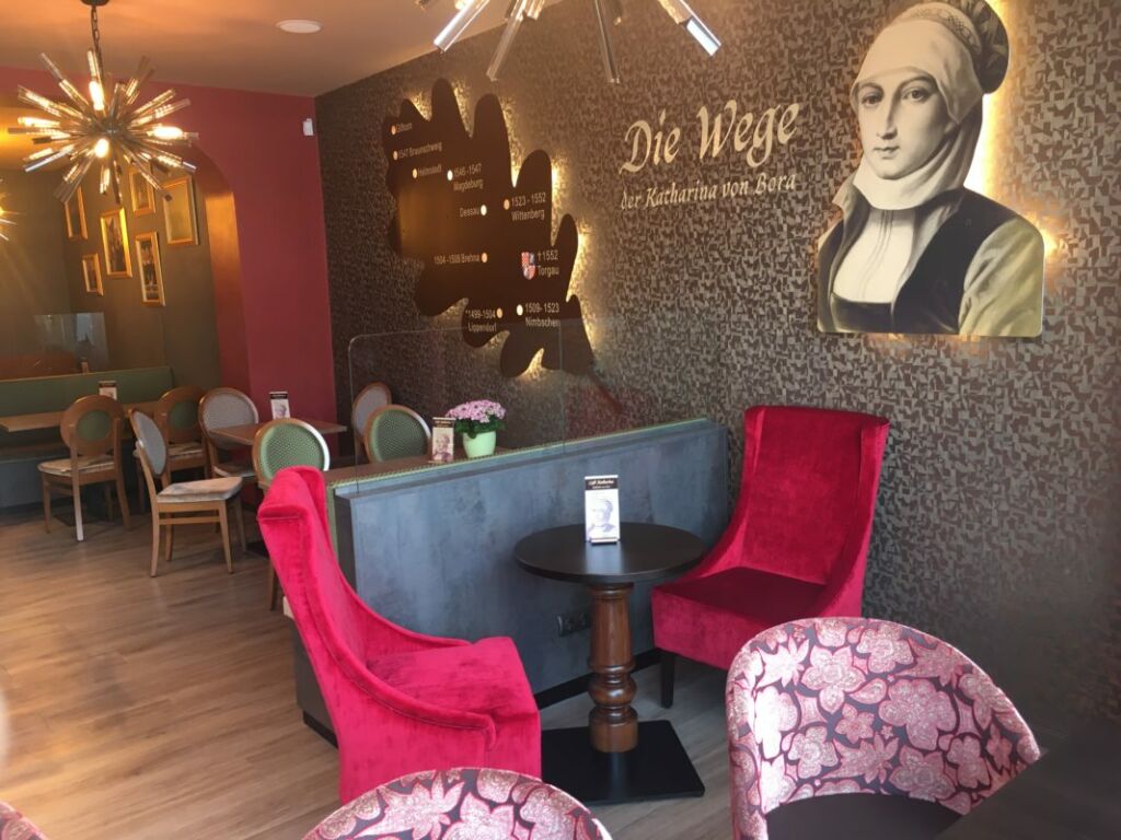 Moderner Sitzbereich mit roten Sesseln, grauem Tisch und Wanddekoration mit Porträt