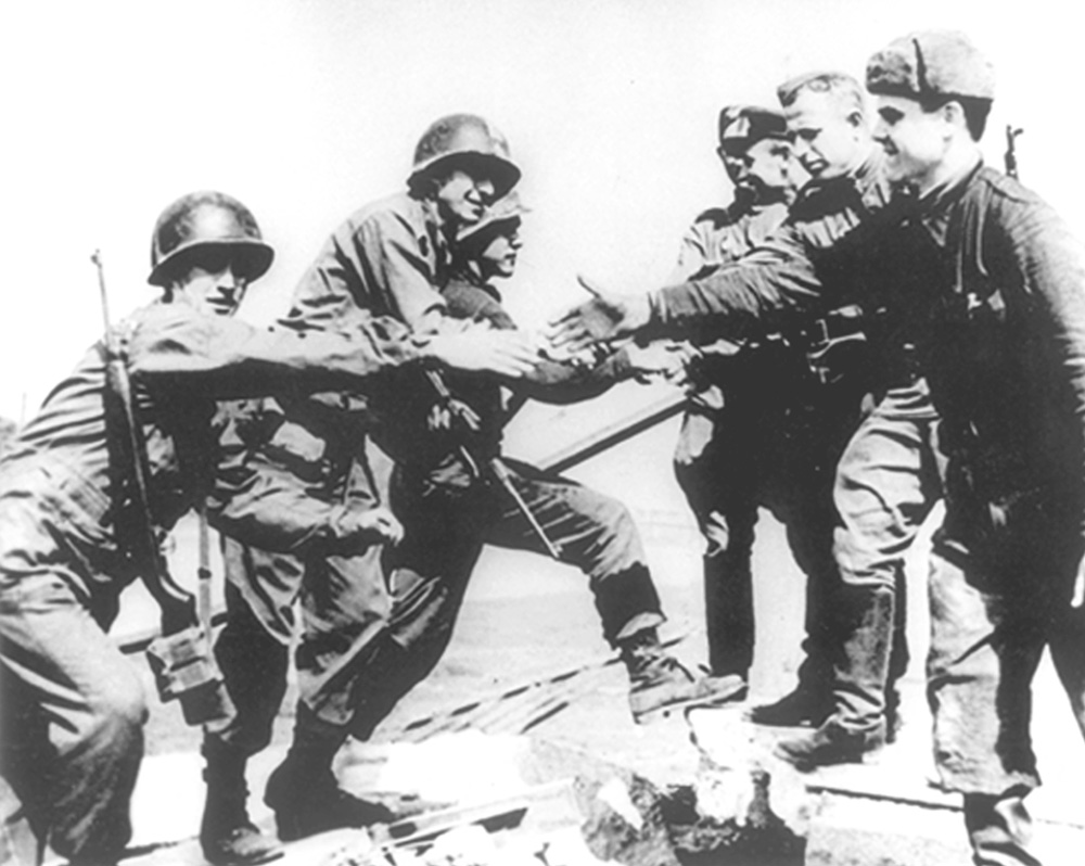 Soldaten geben sich am Elbeufer im April 1945 die Hand. Das Bild ist schwarz-weiß. 